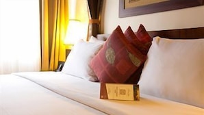 A hotel room with a neatly made bed, pillows, a bedside table with a lamp, and a framed picture on the wall. - African Regent Hotel (Accra)