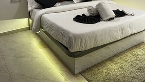 Ein modernes Hotelzimmer mit einem Bett, einem Deckenventilator, einer Klimaanlage und gerahmten Kunstwerken an der Wand.