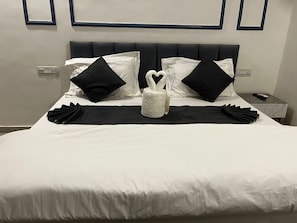 A neatly made bed with a black and white pillow set, a white throw pillow, and a white towel on a black bed runner. - Zista Inn (Shrivardhan)