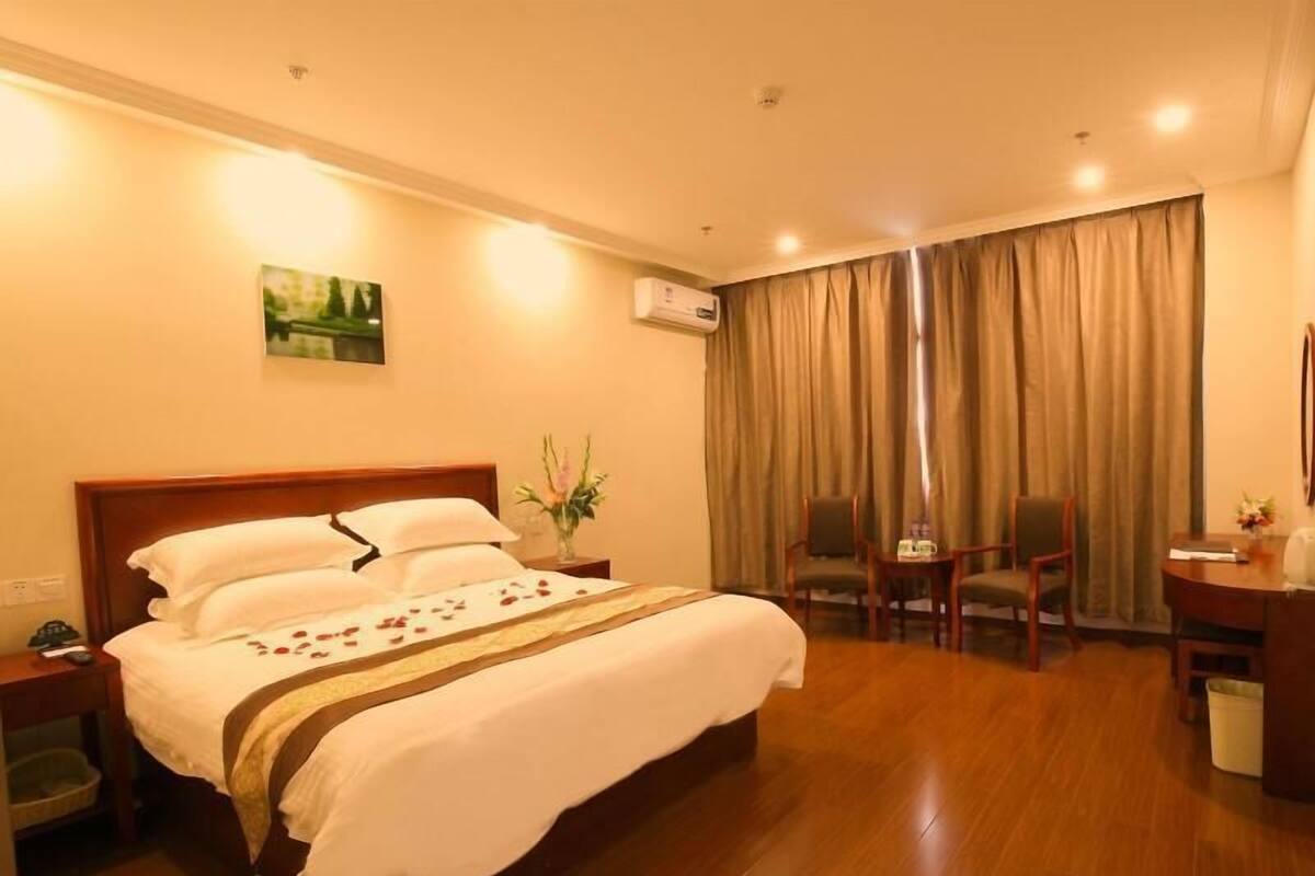 A hotel room with a bed, a desk, a chair, and a window with curtains.