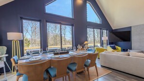 Un espace repas comprenant une table ronde, des chaises et un téléviseur fixé au mur.