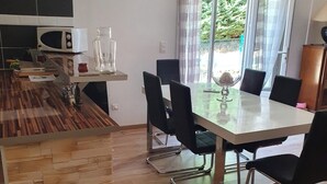Une cuisine moderne équipée d’un four à micro-ondes, d’une table à manger avec des chaises, et offrant une vue sur la verdure environnante.