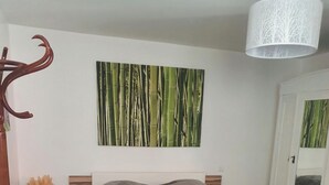 Une chambre à coucher avec un lit, une œuvre d’art accrochée au mur, une table de chevet, un tapis rouge et un tapis à motifs sur le sol.