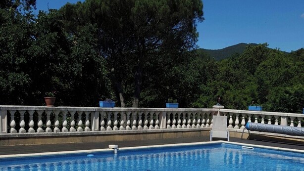 Une piscine dotée d’une balustrade blanche, entourée d’une terrasse carrelée.