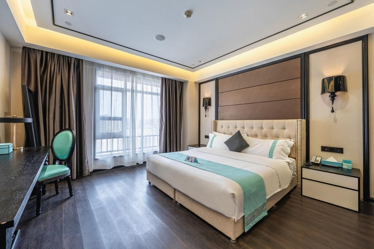 A hotel room with a bed, bedside tables, a desk, and a chair.