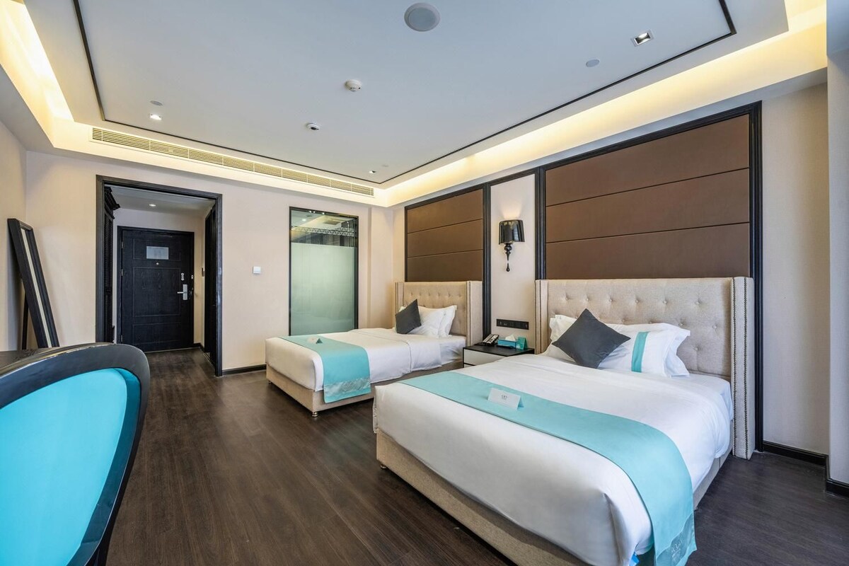 A hotel room with two beds, a desk, and a chair.