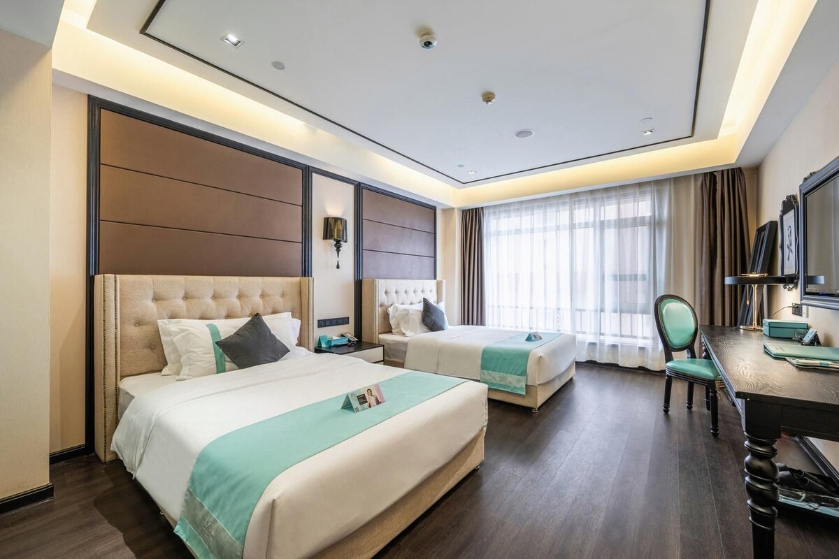A hotel room with two beds, a desk, and a chair.