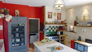 Eine Küche mit roter Wand, weißer Arbeitsplatte und verschiedenen Geräten, darunter ein Herd und ein Kühlschrank.