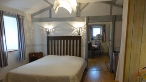 Ein Schlafzimmer mit zwei Betten, Holzboden, einem Kopfteil und einem Fenster mit Vorhängen.