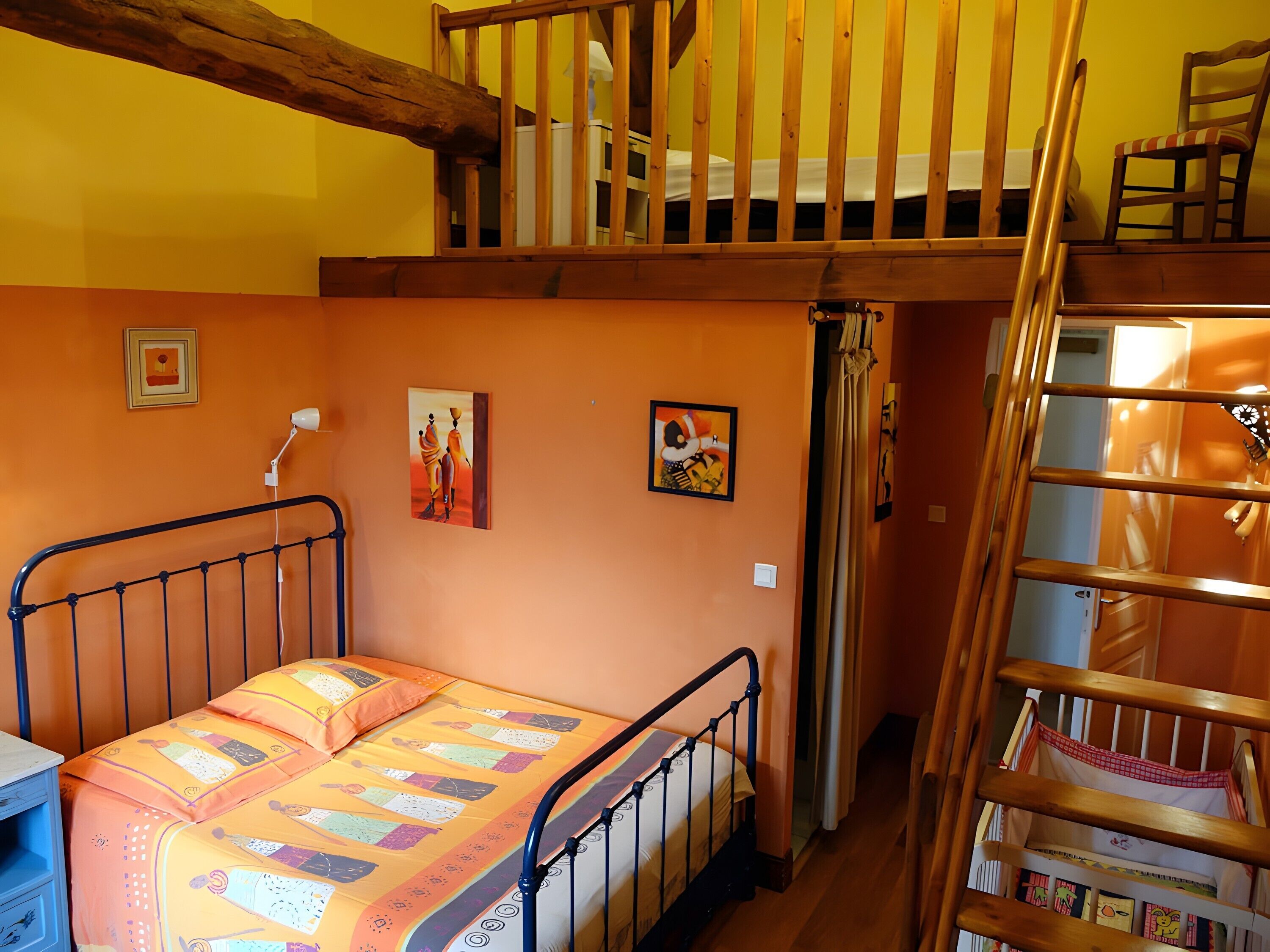 Un dormitorio con una cama litera, una escalera, una mesita de noche y dos cuadros colgados en la pared.