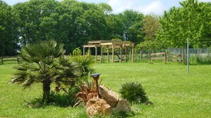 Un kiosque se dresse dans un champ verdoyant, avec des arbres en arrière-plan.