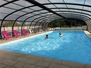 Une piscine couverte avec des chaises et une clôture.