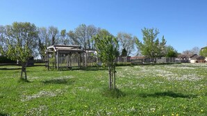 Un parque con un pérgola, árboles y un campo cubierto de césped y flores.