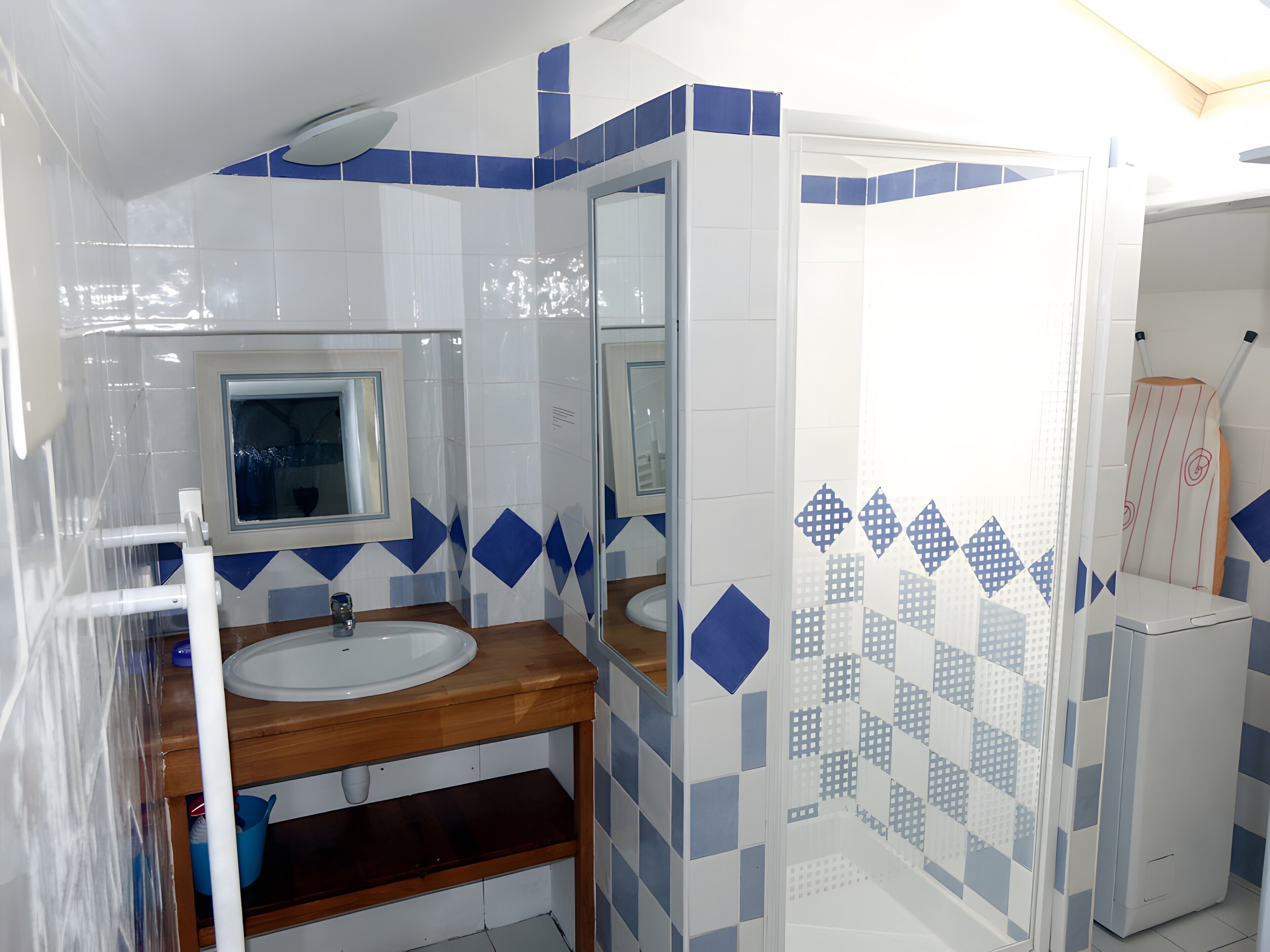 A bathroom with a sink, mirror, and shower area.