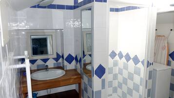 A bathroom with a sink, mirror, and shower area.