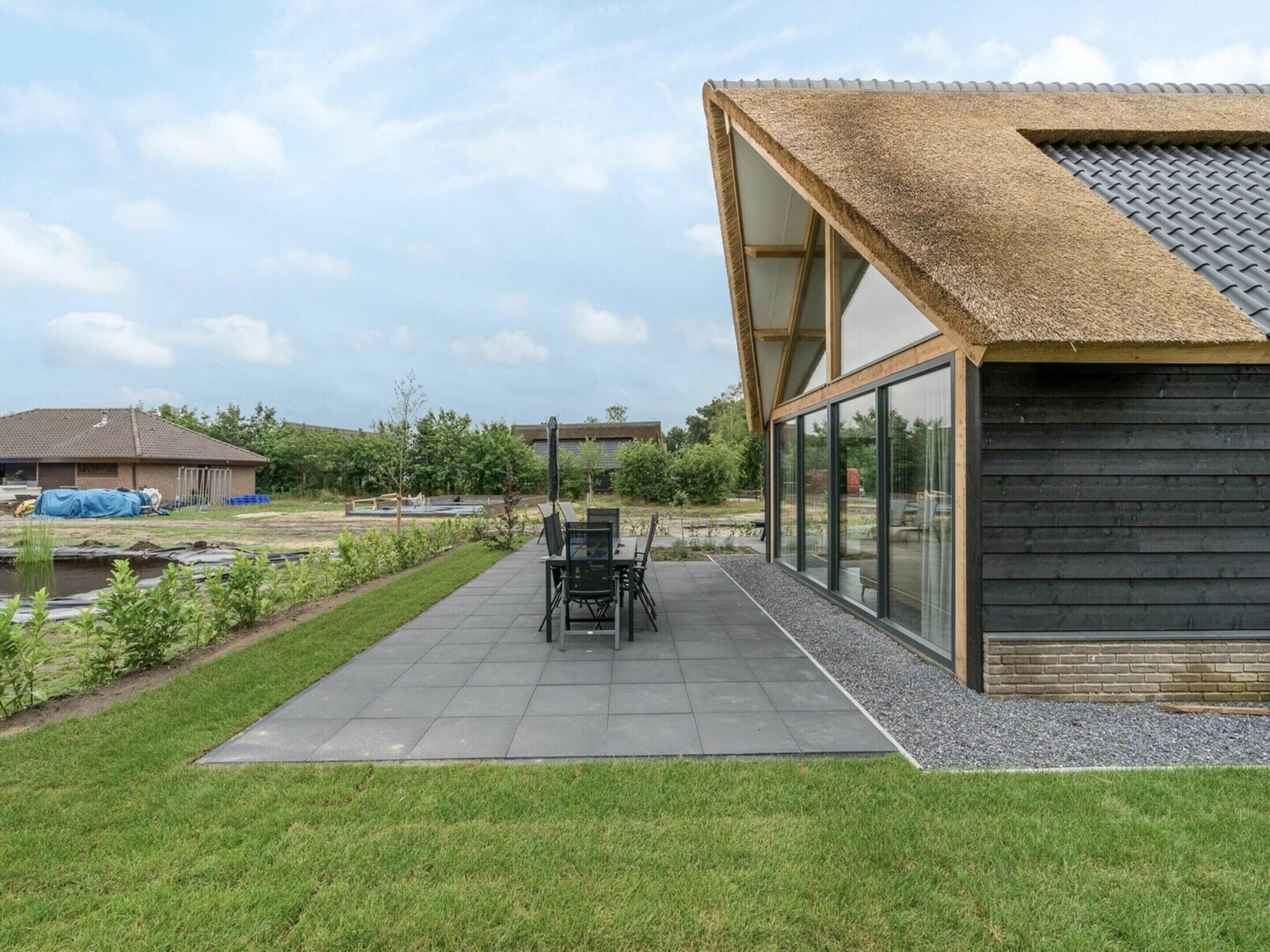 Una casa moderna con un patio, un comedor y un amplio ventanal.