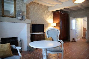 Uma sala de estar com lareira, televisão, mesa de jantar e uma cadeira.