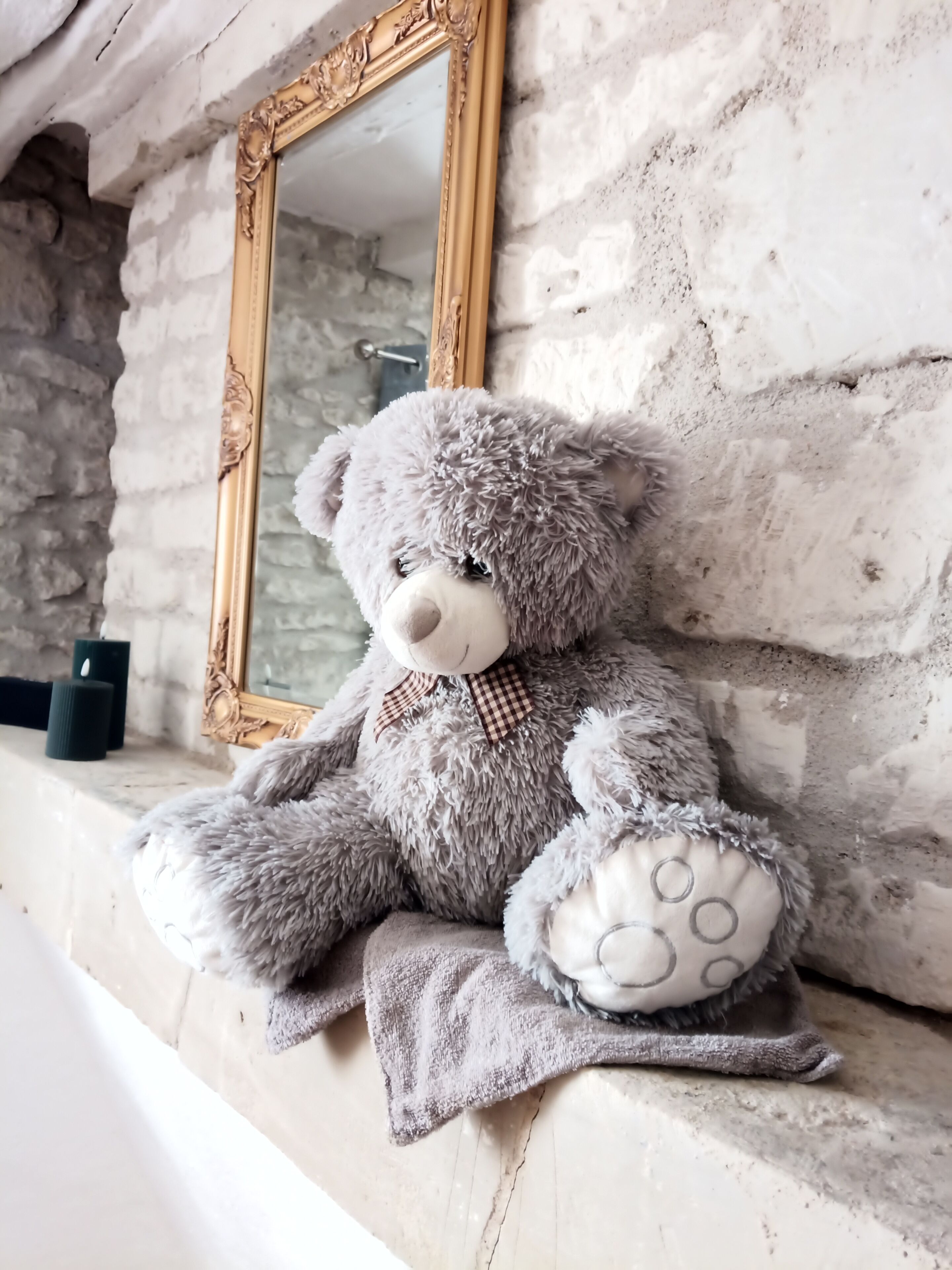 Een zachtaardig teddybeer op een plank met een spiegel en kaarsen.