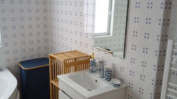 A bathroom with a white sink, mirror, and patterned tiles.