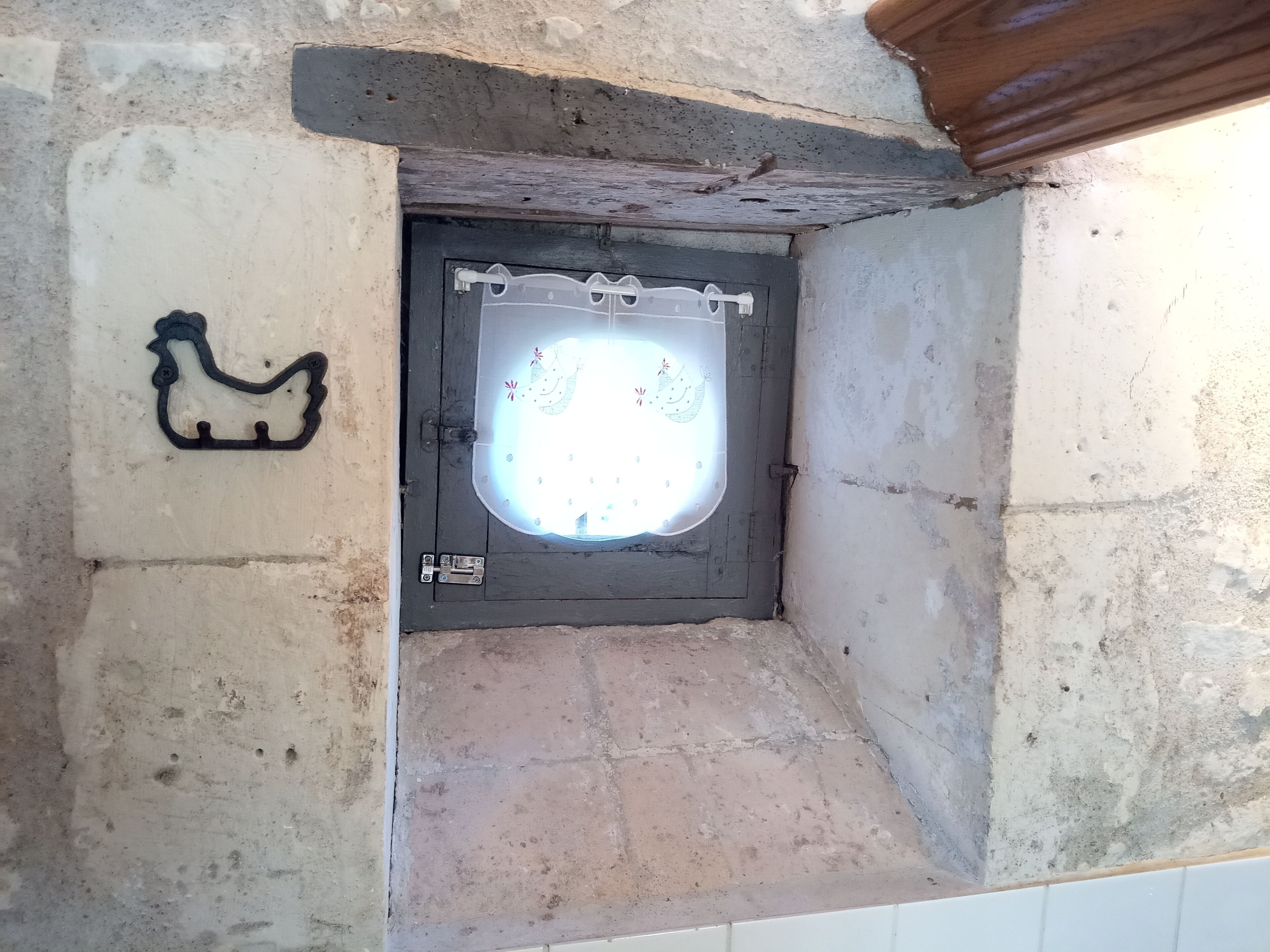 Casa de banho com paredes de pedra, zona de chuveiro, suporte para toalhas e uma pequena janela.