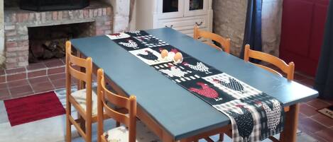 A dining area with a table set for four, a fireplace, a cabinet, and a red door.