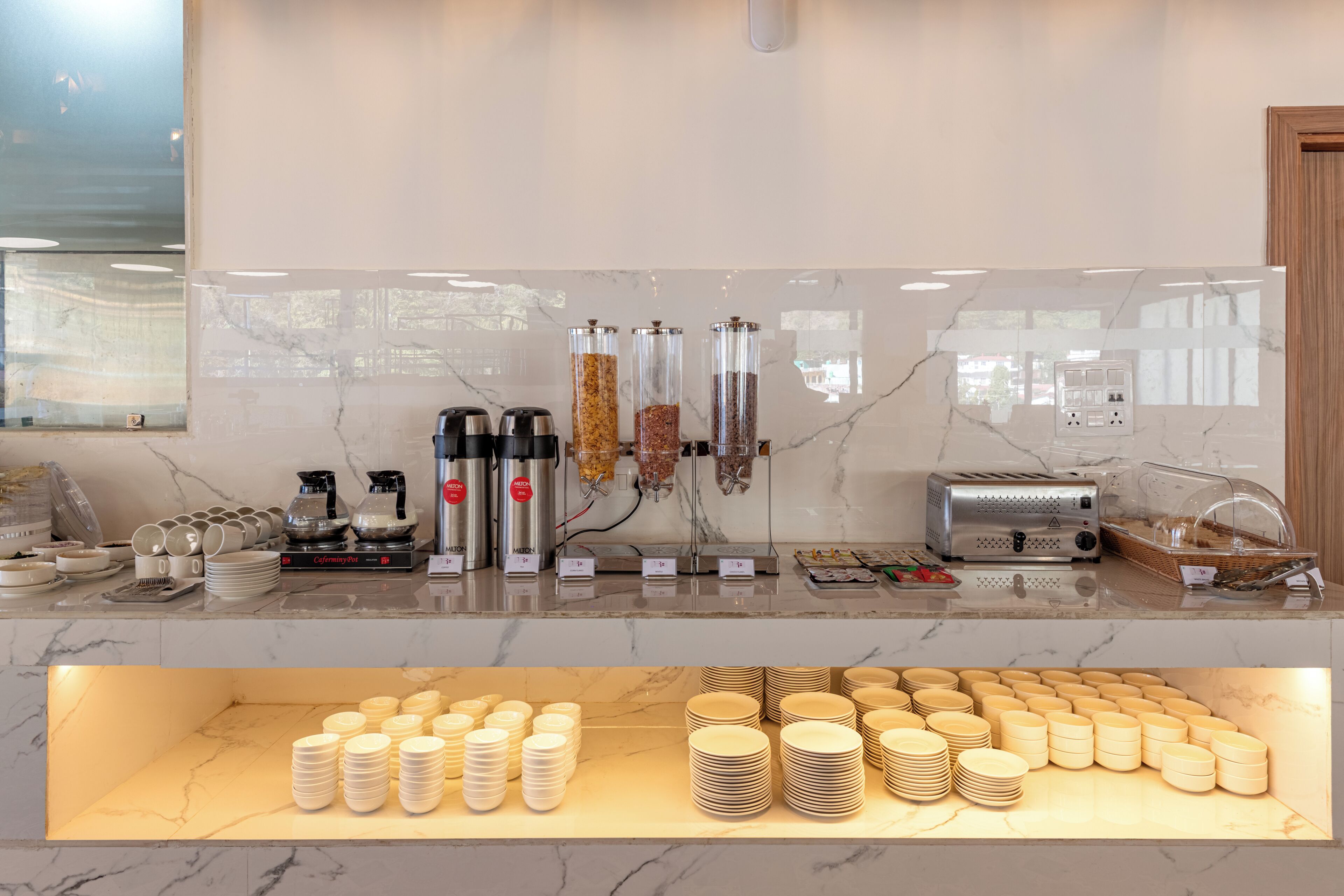 Ein Buffet mit verschiedenen Speisenausgabestationen, einem Toaster und einer Anordnung gestapelter Teller.