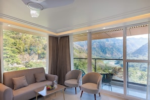 Ein modernes Zimmer mit einer Couch, Stühlen, einem Tisch und einem großen Fenster mit Blick auf die Berge.