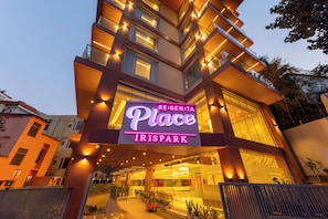 Ein Hotel Eingang mit einem Neonlichtschild, auf dem 'RE:GEN:TA Place IRISPARK' steht, und einem modernen architektonischen Design.