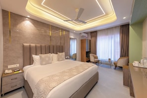 Ein modernes Hotelzimmer mit einem großen Bett, einem Schreibtisch, einem Sessel und einem Deckenventilator.