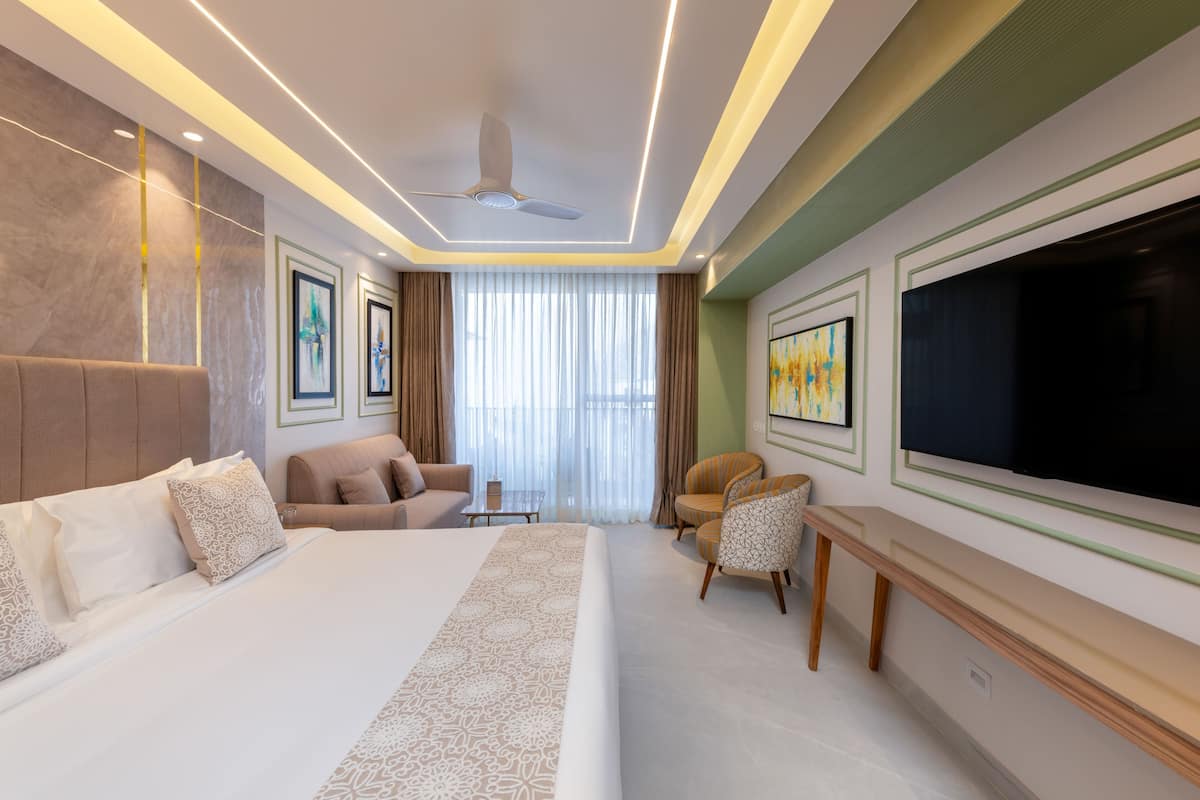Una habitación de hotel moderna con una cama grande, un sofá, una silla, un televisor y un ventilador de techo.