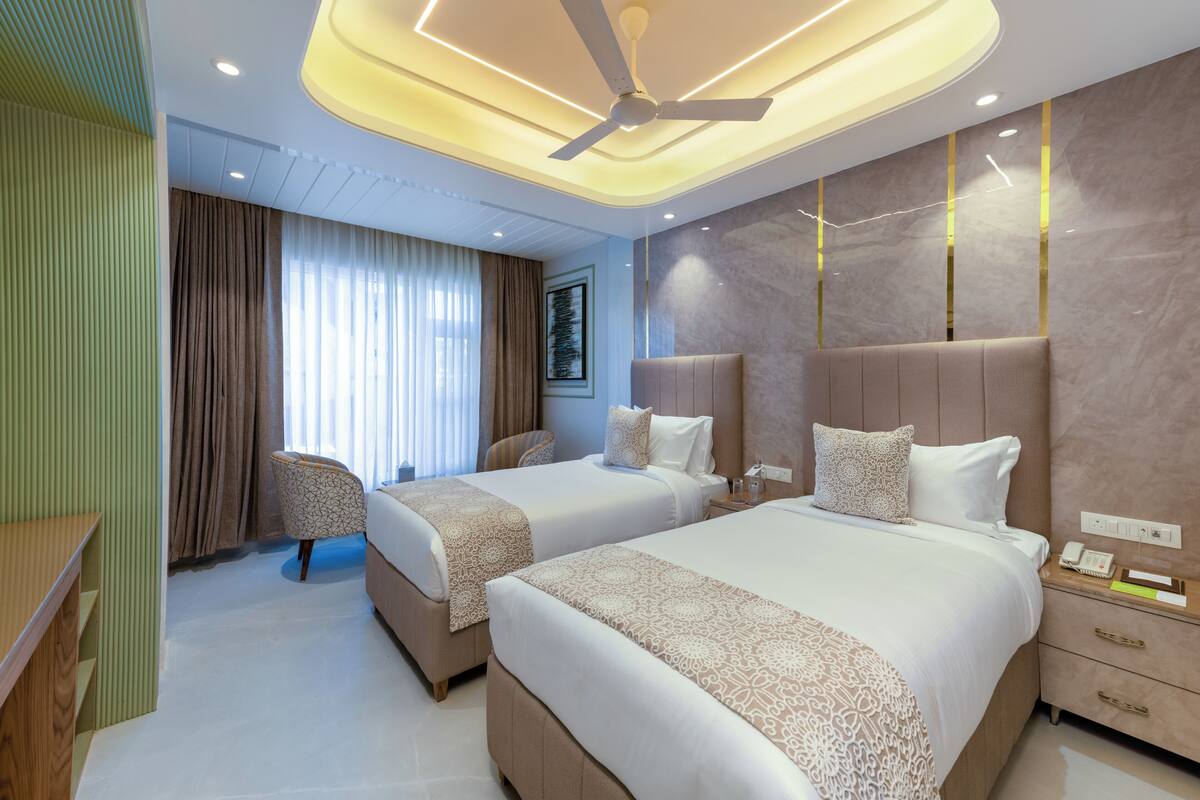 Una habitación de hotel con dos camas, un ventilador de techo, un escritorio y una silla.