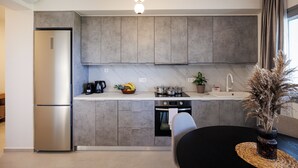 A modern kitchen with grey cabinets, a stainless steel refrigerator, a coffee maker, and a potted plant. - Etherio Naxos Anemos Tranquil 2-bedroom apartment with AC in beautiful Naxos (Naxos)