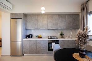 A modern kitchen with grey cabinets, a stainless steel refrigerator, a coffee maker, and a potted plant. - Etherio Naxos Anemos Tranquil 2-bedroom apartment with AC in beautiful Naxos (Naxos)