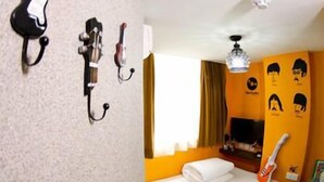A hotel room with a bed, a guitar, a TV, and wall art. - Tempo Inn @david Mansion (Kowloon)