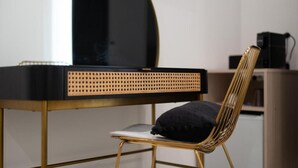 Een stoel met een gevlochten rugleuning, een zwart bureau met een geperforeerde zijkant en een zwart voorwerp op het bureau.