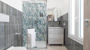Een badkamer met douche, toilet en wastafel met spiegel.
