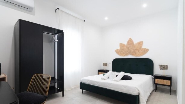 Een moderne slaapkamer met een bed, een stoel, een kledingkast en een kunstwerk aan de muur.