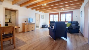 A spacious living area with wooden beams, a dining table, and a sofa. - Apartment 'Rheinaue' with Shared Garden, Balcony and Wi-Fi (Neuried)