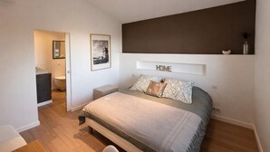Een slaapkamer met een bed, nachtkastjes, een kaptafel, een spiegel en een lijst met een afbeelding aan de muur.