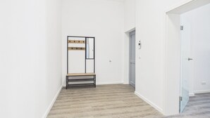 Un couloir avec un porte-manteau, un banc et une porte donnant sur une autre pièce.