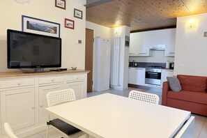 Eine moderne Küche mit weißen Schränken, einem Einbauofen und einem Essbereich mit weißem Tisch und Stühlen.