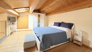 Ein Schlafzimmer mit einem Bett, einem Nachttisch, einem Fernseher und einem Kleiderschrank.