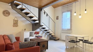 Ein modernes Interieur mit Treppe, einer Couch, einem Esstisch und Pendelleuchten.