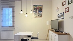 Ein modernes Wohnzimmer mit Essbereich, Fernseher und Kunstwerken an der Wand.