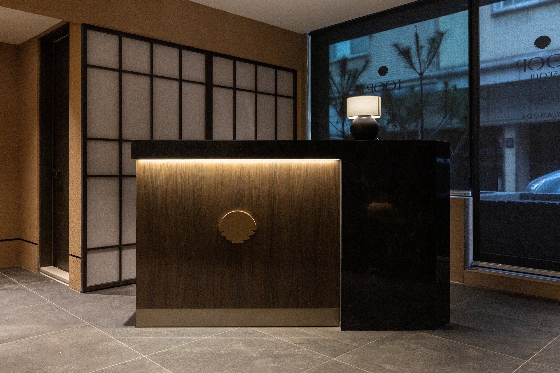 Un mostrador de recepción con detalles de madera y un separador de vidrio.