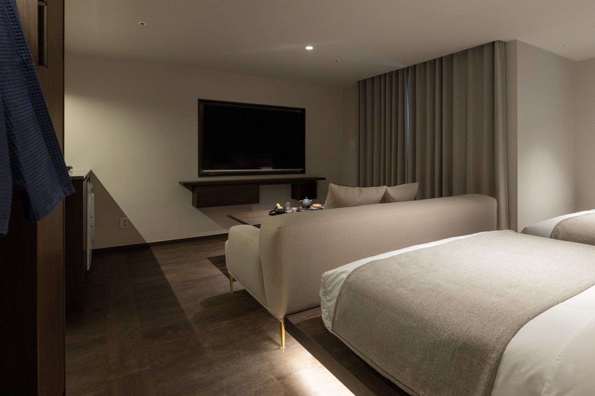 Ein modernes Hotelzimmer mit Bett, Fernseher und Schreibtisch mit Stuhl.