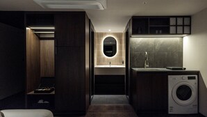 A compact, modern bathroom with a built-in washing machine, a sink with a mirror, and a small seating area. - LOOP Seoul Hotel Retreat by Anook Seoul Gangnam 1 (Seoul)