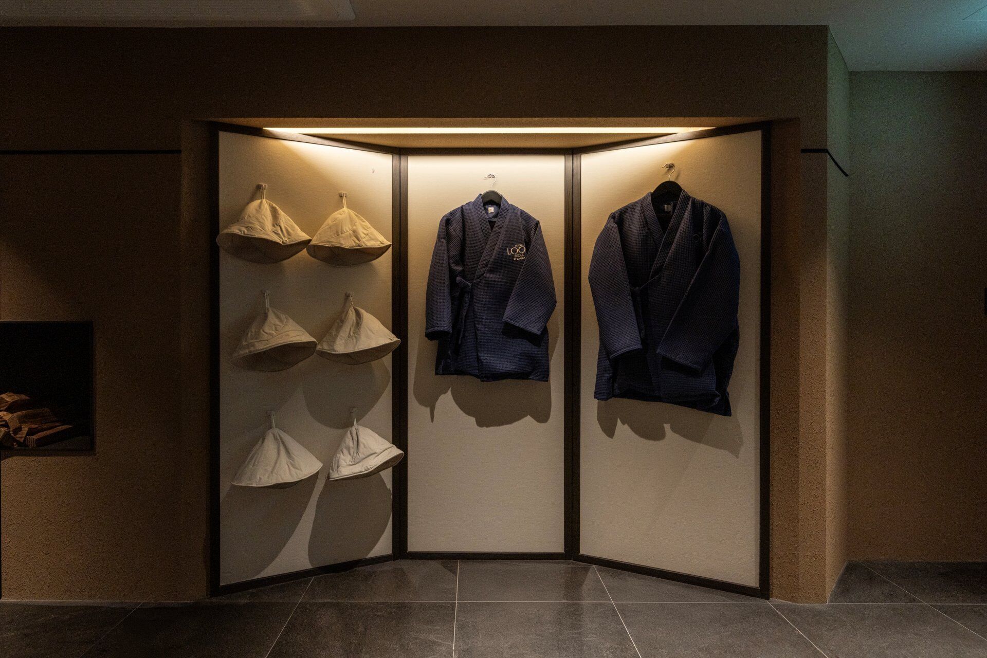 Een hoekzaal met een scheidingswand waarop hoeden en twee jassen hangen.