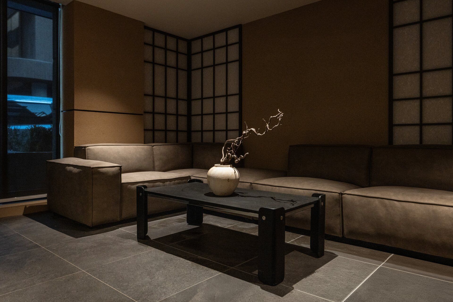 A modern living room with a sofa, a coffee table, and a vase with branches.