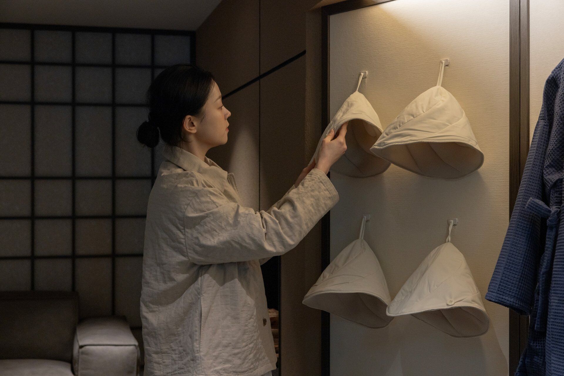 A person holding a bra in a room with a wardrobe and a toilet.